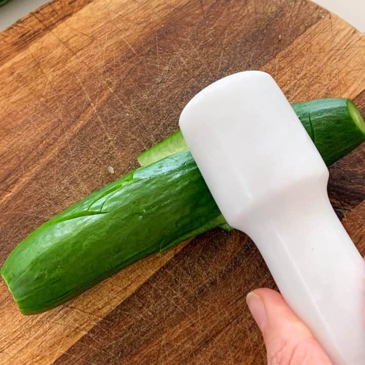 photo is showing how to smash cucumber with a rolling pin.