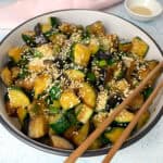 Eggplant and zucchini stir fry served in a white bowl.
