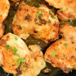 Crispy baked chicken thighs in a frying pan.