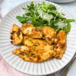 Chicken piccata served with rocket salad and fresh parsley.