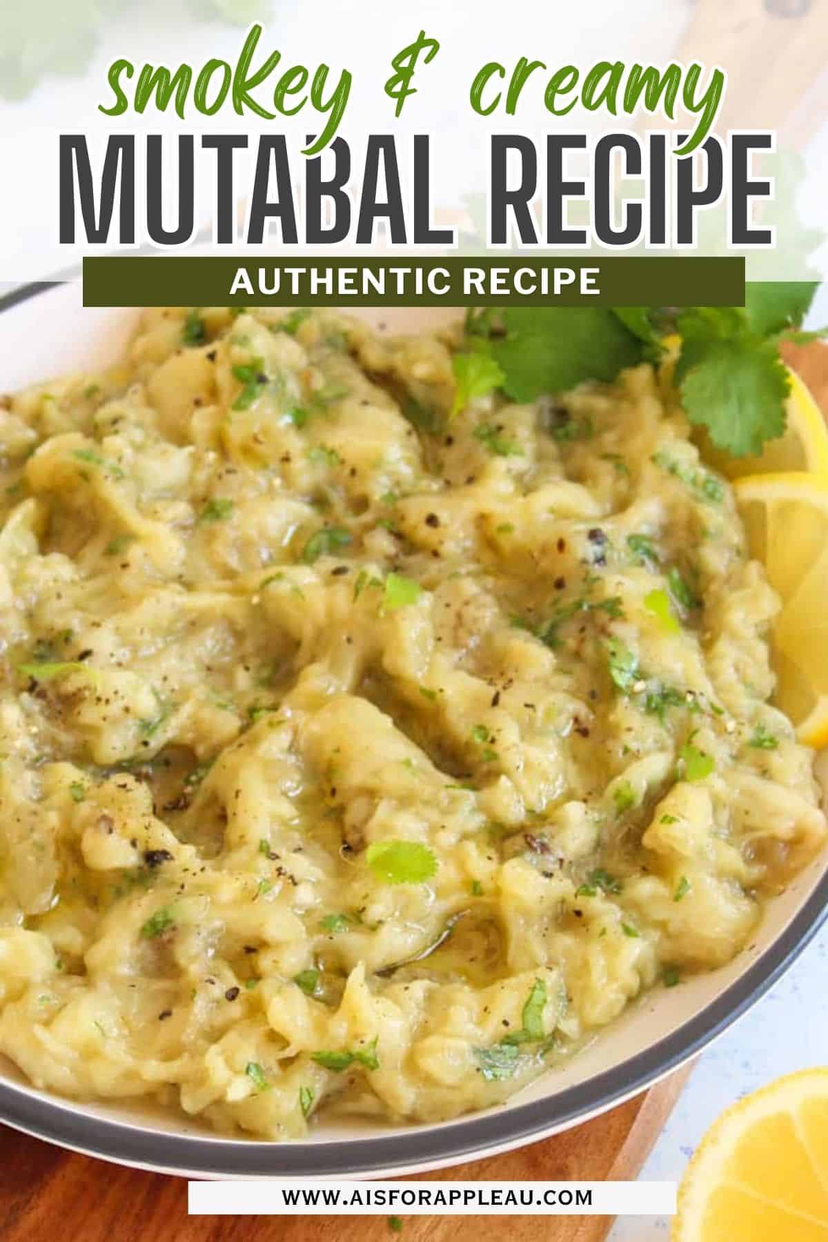 A bowl of creamy mutabal topped with herbs and seasonings, garnished with lemon slices and fresh parsley. Text overlay reads, Smokey & Creamy Mutabal Recipe - Authentic Recipe. A web address is visible at the bottom.