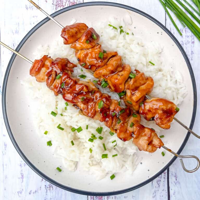 Easy teriyaki chicken skewers served over steamed rice with chopped chives.